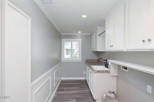 clothes washing area featuring cabinets, crown molding, sink, hardwood / wood-style flooring, and washer hookup