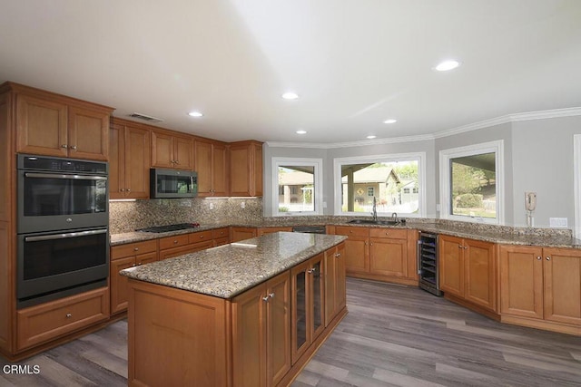 kitchen featuring stainless steel appliances, tasteful backsplash, light stone counters, hardwood / wood-style flooring, and ornamental molding