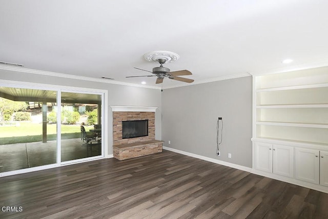 unfurnished living room with ceiling fan, a fireplace, ornamental molding, and dark wood-type flooring