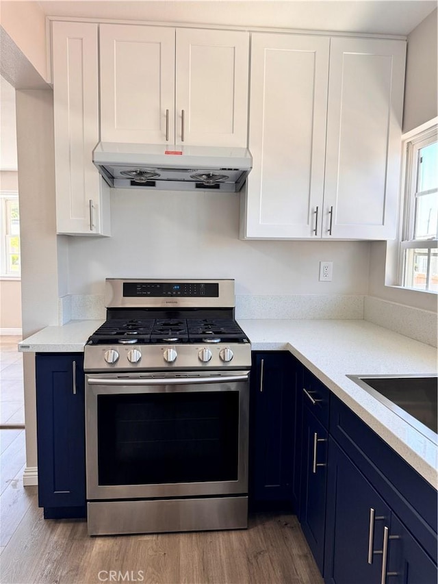 kitchen with white cabinets, light hardwood / wood-style floors, and stainless steel gas range