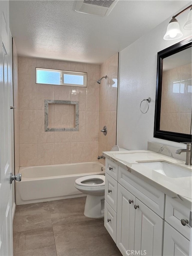 full bathroom featuring vanity, toilet, a textured ceiling, and tiled shower / bath