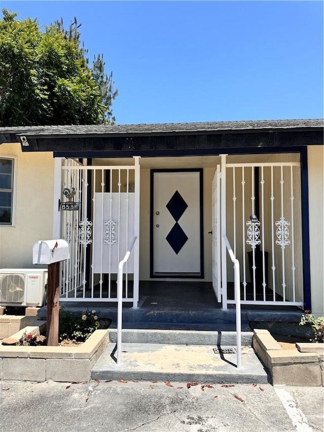 view of exterior entry featuring ac unit and a porch