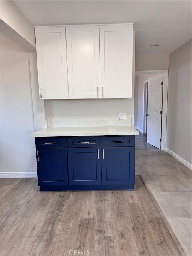 kitchen featuring blue cabinetry, white cabinetry, and light wood-type flooring