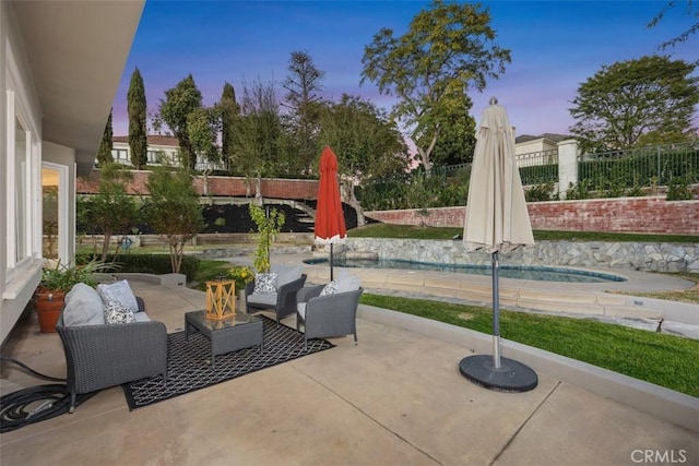 patio terrace at dusk with a fenced backyard and an outdoor living space