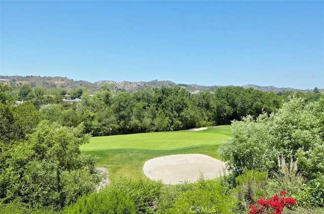 view of home's community featuring view of golf course, a yard, a wooded view, and a mountain view