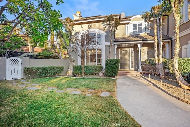 view of front facade with a front yard, a gate, fence, and stucco siding