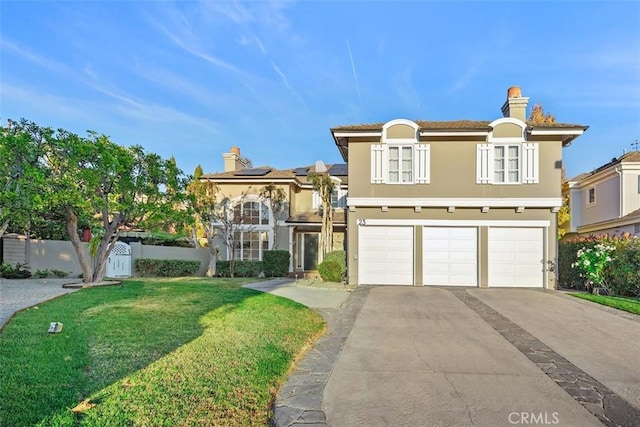 view of front of property with stucco siding, concrete driveway, fence, a garage, and a front lawn