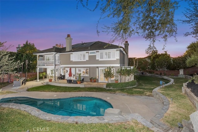 back of property with a balcony, a fenced backyard, a yard, a patio area, and stucco siding