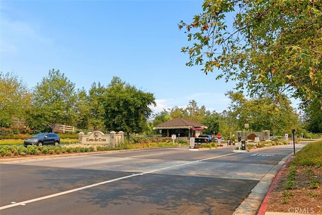 view of street featuring curbs, a gated entry, and traffic signs