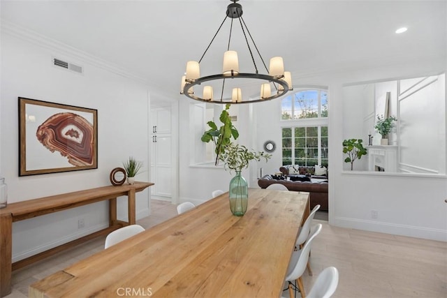 dining space with baseboards, visible vents, ornamental molding, an inviting chandelier, and light wood-style floors