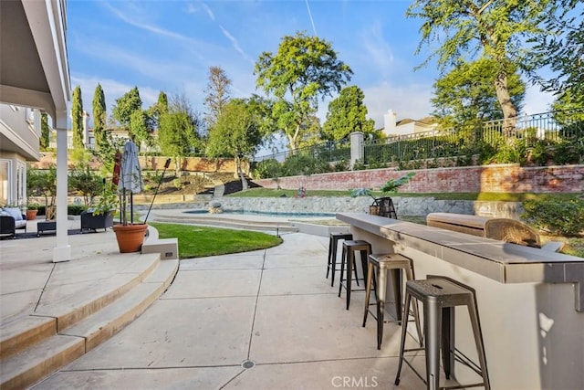 view of patio / terrace featuring fence and outdoor dry bar