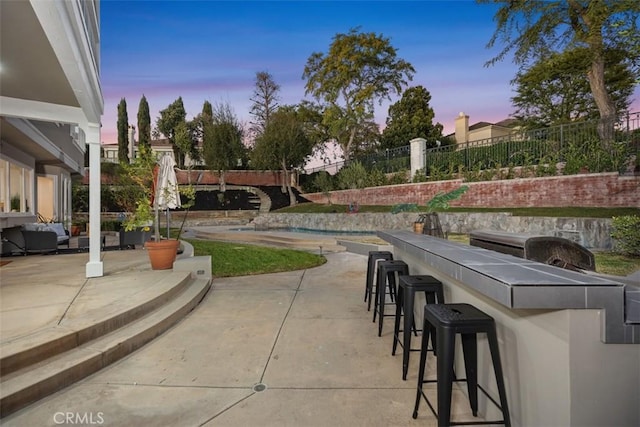 patio terrace at dusk with an outdoor bar and fence