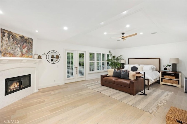 bedroom featuring recessed lighting, wood finished floors, access to outside, french doors, and a glass covered fireplace