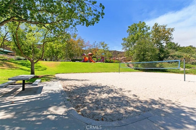 view of property's community featuring playground community, a lawn, and volleyball court