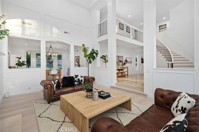 living room featuring a chandelier, light hardwood / wood-style floors, and a high ceiling