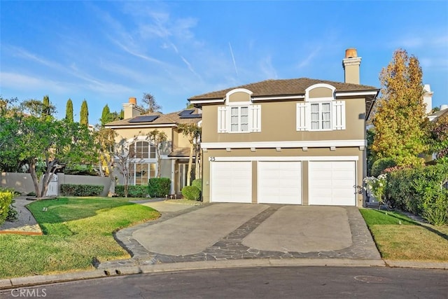 view of front of house featuring a garage, driveway, solar panels, and stucco siding