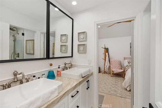 ensuite bathroom featuring double vanity, ensuite bath, a sink, and a shower stall