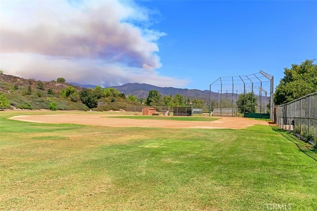 view of community with fence, a lawn, and a mountain view