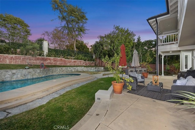 patio terrace at dusk featuring a fenced in pool, a fenced backyard, and an outdoor living space