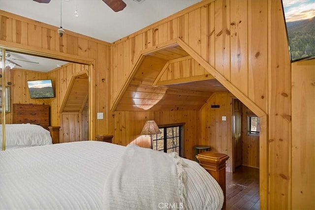 bedroom featuring wooden walls, ceiling fan, and dark hardwood / wood-style floors