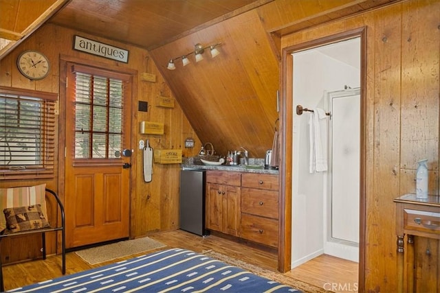 doorway featuring wood ceiling, wooden walls, light hardwood / wood-style floors, and vaulted ceiling