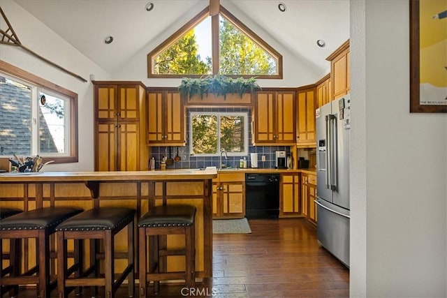 kitchen with decorative backsplash, high end refrigerator, plenty of natural light, and black dishwasher