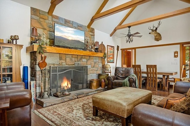 living room featuring ceiling fan, beam ceiling, high vaulted ceiling, hardwood / wood-style floors, and a stone fireplace