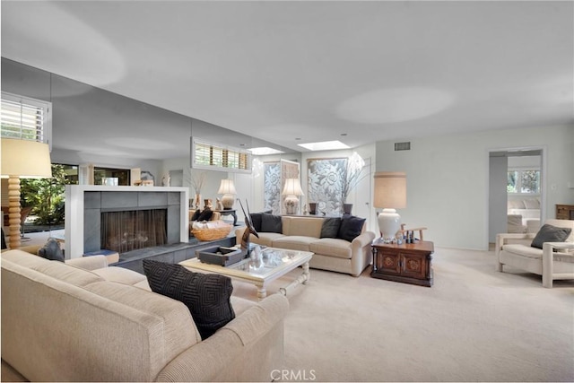 living room featuring a tile fireplace, a wealth of natural light, and carpet