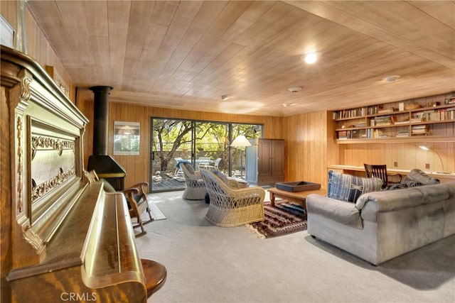 carpeted living room featuring wooden ceiling, wooden walls, and a wood stove