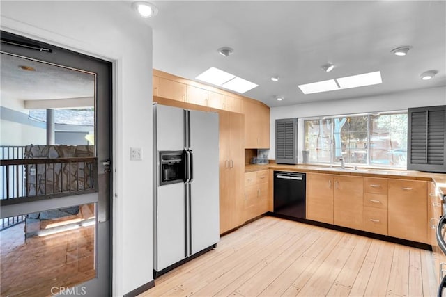 kitchen featuring dishwasher, a healthy amount of sunlight, white refrigerator with ice dispenser, and a skylight