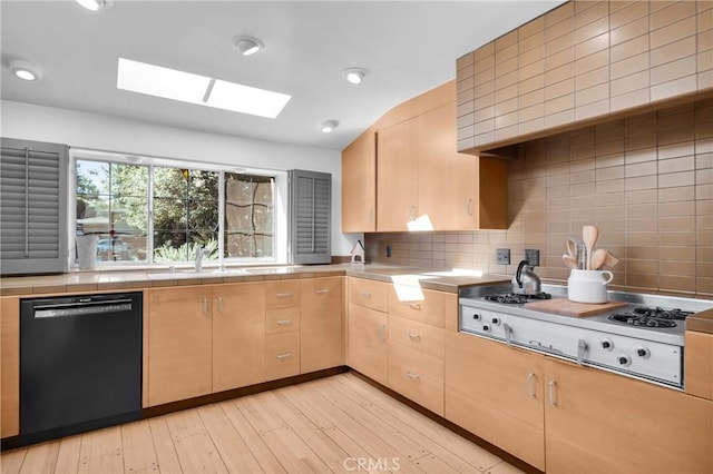 kitchen with stainless steel gas stovetop, dishwasher, sink, light hardwood / wood-style flooring, and a skylight