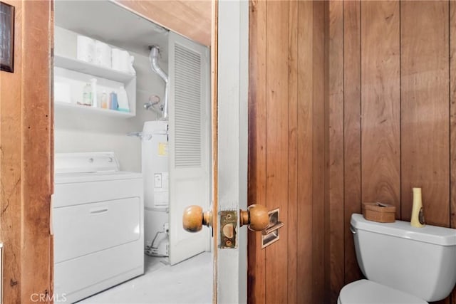 bathroom featuring wood walls, toilet, gas water heater, and washer / dryer