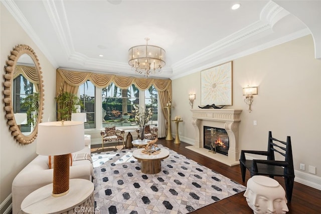 sitting room with a tray ceiling, dark hardwood / wood-style flooring, a notable chandelier, and ornamental molding