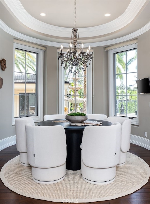 dining space with a tray ceiling, ornamental molding, dark wood-type flooring, and an inviting chandelier