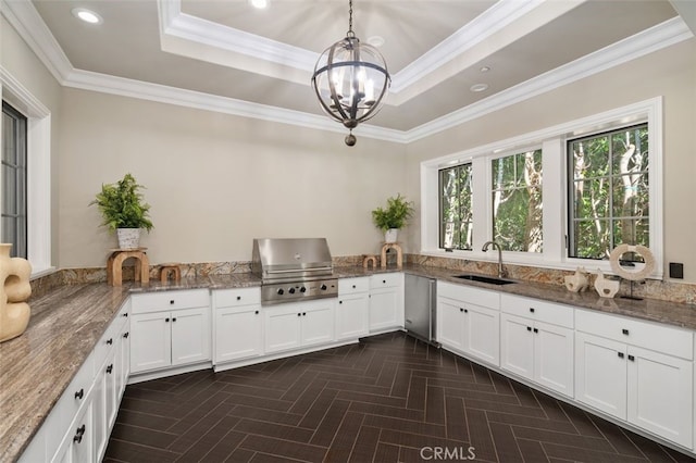 kitchen featuring white cabinetry, sink, hanging light fixtures, stone countertops, and ornamental molding