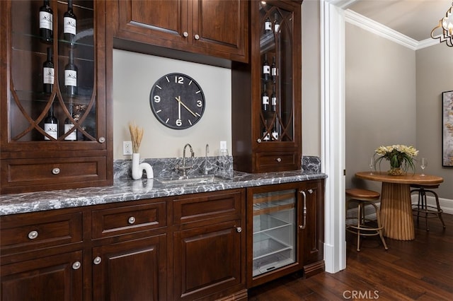 bar with dark brown cabinets, sink, ornamental molding, and dark wood-type flooring