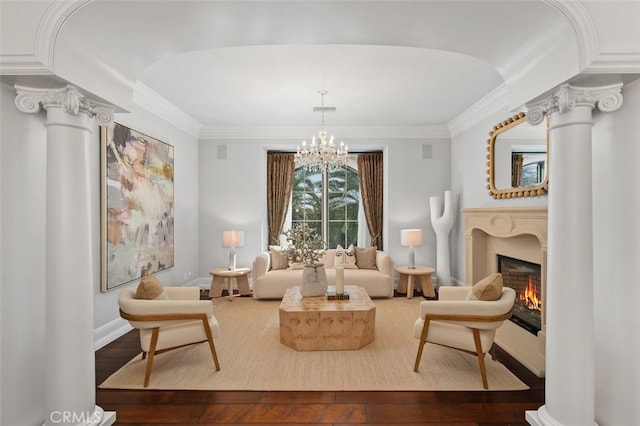 living room with hardwood / wood-style flooring, a notable chandelier, ornate columns, and crown molding