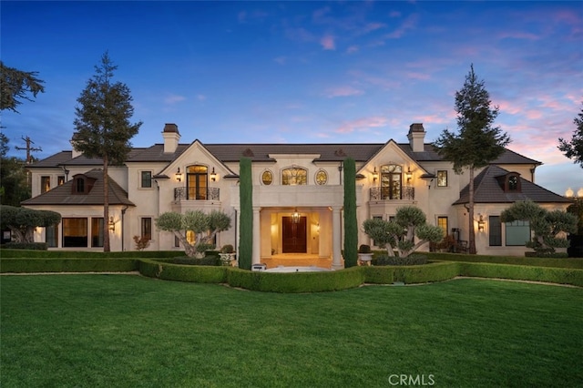 french country inspired facade with a yard and a balcony