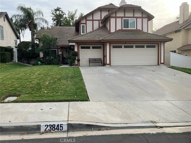 tudor home featuring a front yard and a garage