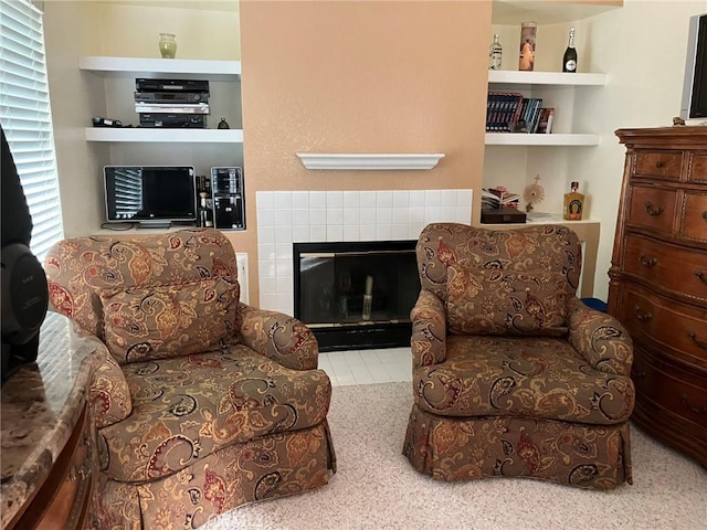 sitting room with a tile fireplace, built in shelves, and carpet floors