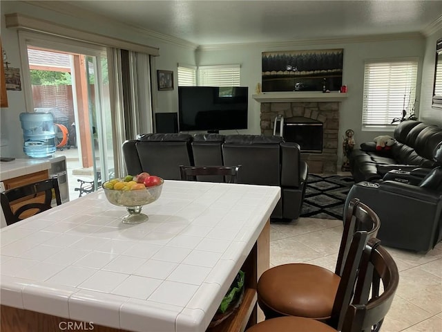 tiled dining space featuring a stone fireplace and crown molding