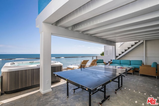 view of patio featuring cooling unit, outdoor lounge area, a water view, and a hot tub