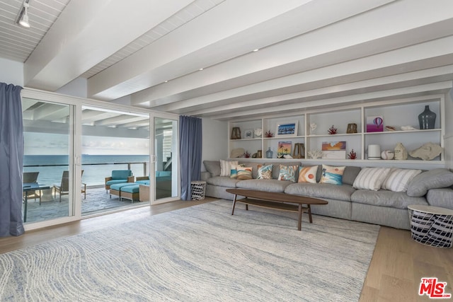 living room featuring beamed ceiling, a water view, and wood-type flooring