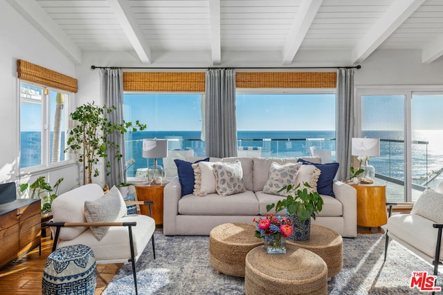 sunroom with beamed ceiling and a water view