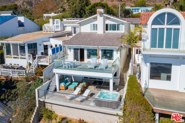 rear view of property with a balcony and a wooden deck