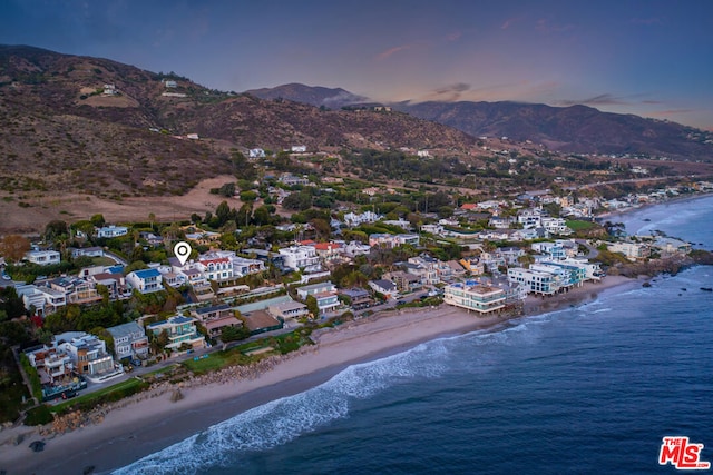 aerial view at dusk with a beach view and a water and mountain view