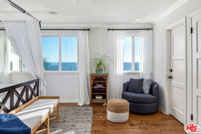 sitting room with hardwood / wood-style floors, ornamental molding, and a healthy amount of sunlight