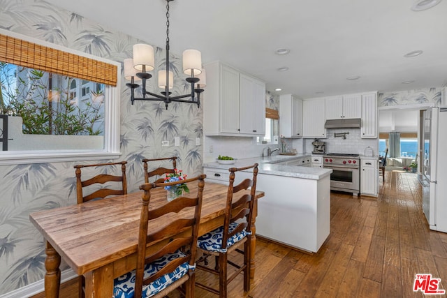 kitchen featuring white cabinets, fridge, premium range, and a notable chandelier