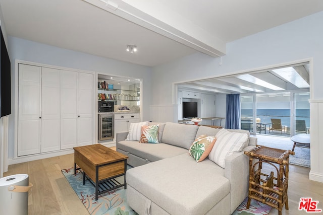 living room with beam ceiling, wine cooler, and light hardwood / wood-style flooring