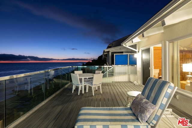 deck at dusk featuring a water view